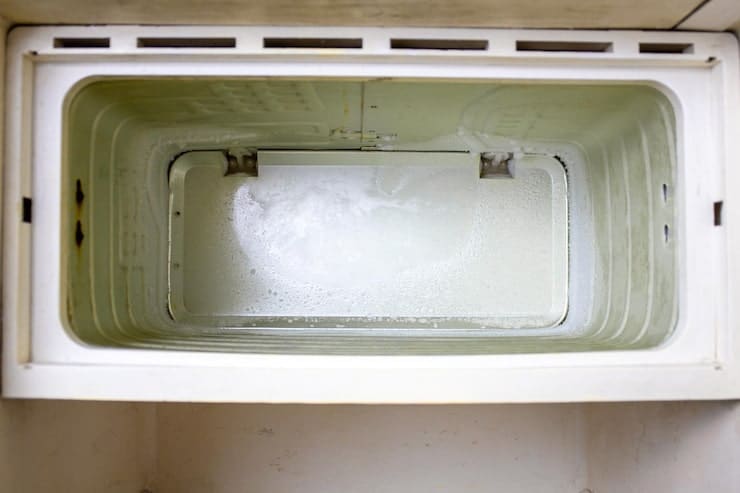 A close-up view of a white rectangular container with a recessed compartment and a curved metal handle inside, photographed from above, Freezer Disposal