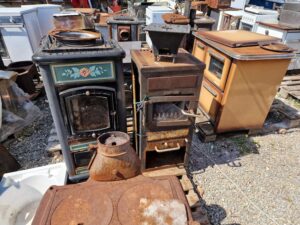 Various vintage stoves and appliances displayed on the ground, highlighting their aged features and historical significance.