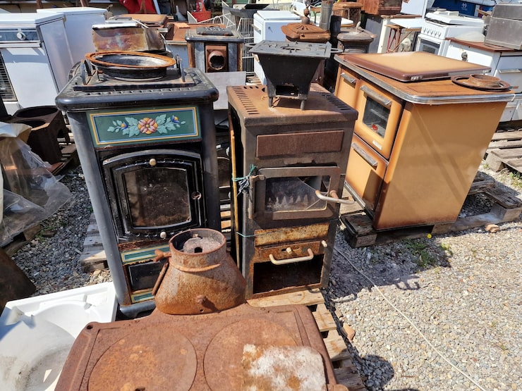 Various vintage stoves and appliances displayed on the ground, highlighting their aged features and historical significance.